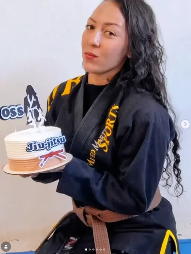 Tamires França com kimono segurando bolo temático de jiu-jitsu